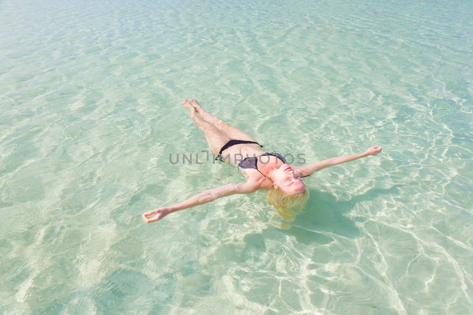 Caucasian lady floating in turquoise sea. by kasto