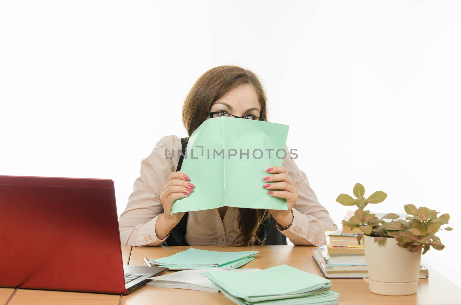 Cute little girl is a teacher sitting at a desk with a laptop, books and notebooks