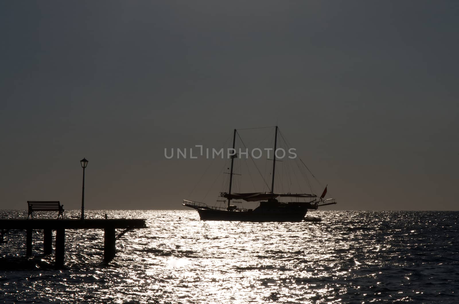 Seascape with Sailing Ship and Pier with Street Lamp Early Morning on Sunrise Sea background Outdoors