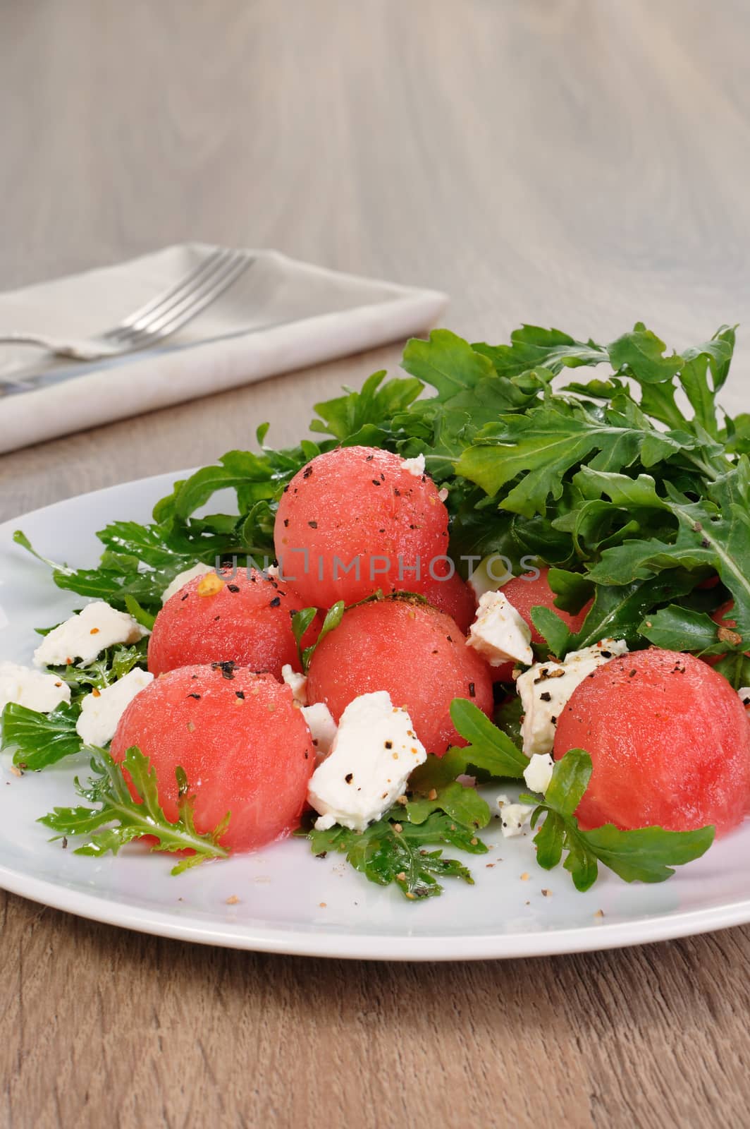 Spicy salad of watermelon balls with arugula and slices of feta