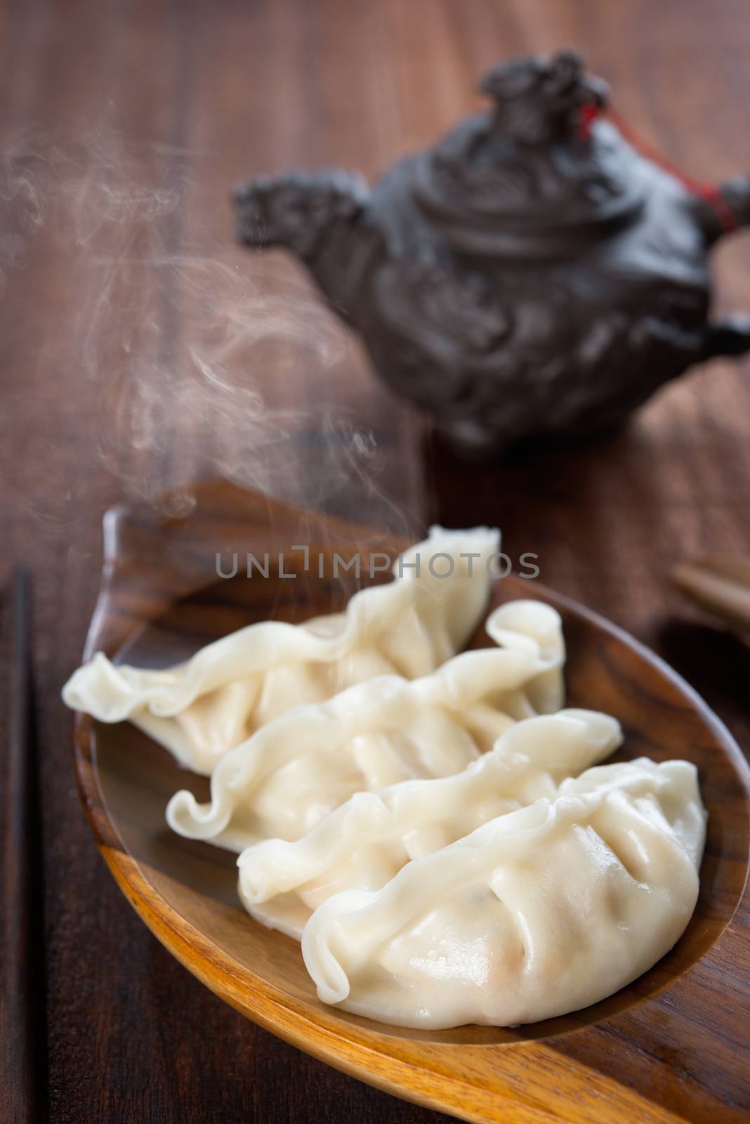 Fresh dumplings with hot steams on wood plate. Delicious Chinese gourmet on rustic old vintage wooden background. 