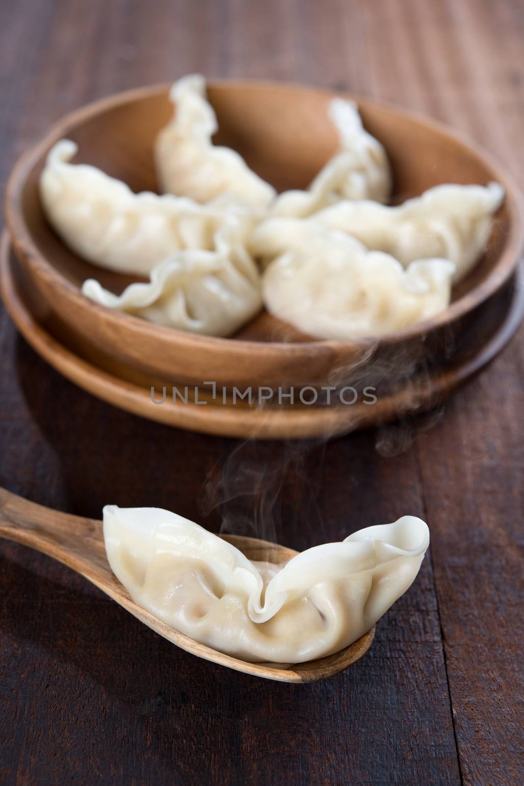 Fresh dumplings with hot steams on wood spoon. Famous Chinese cuisine on rustic old vintage wooden background. 
