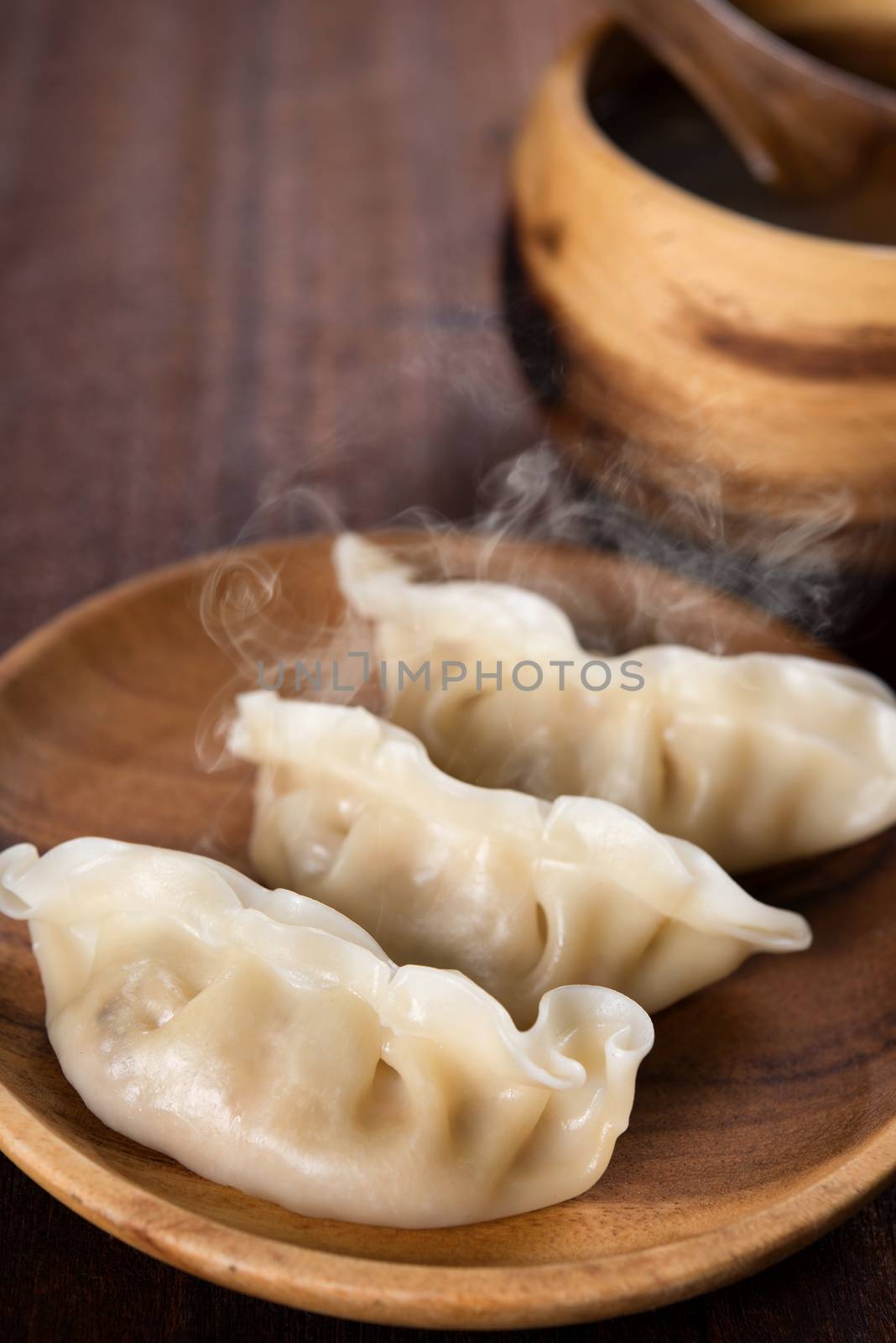 Close up dumplings with hot steams on wood plate. Chinese food on rustic old vintage wooden background. 