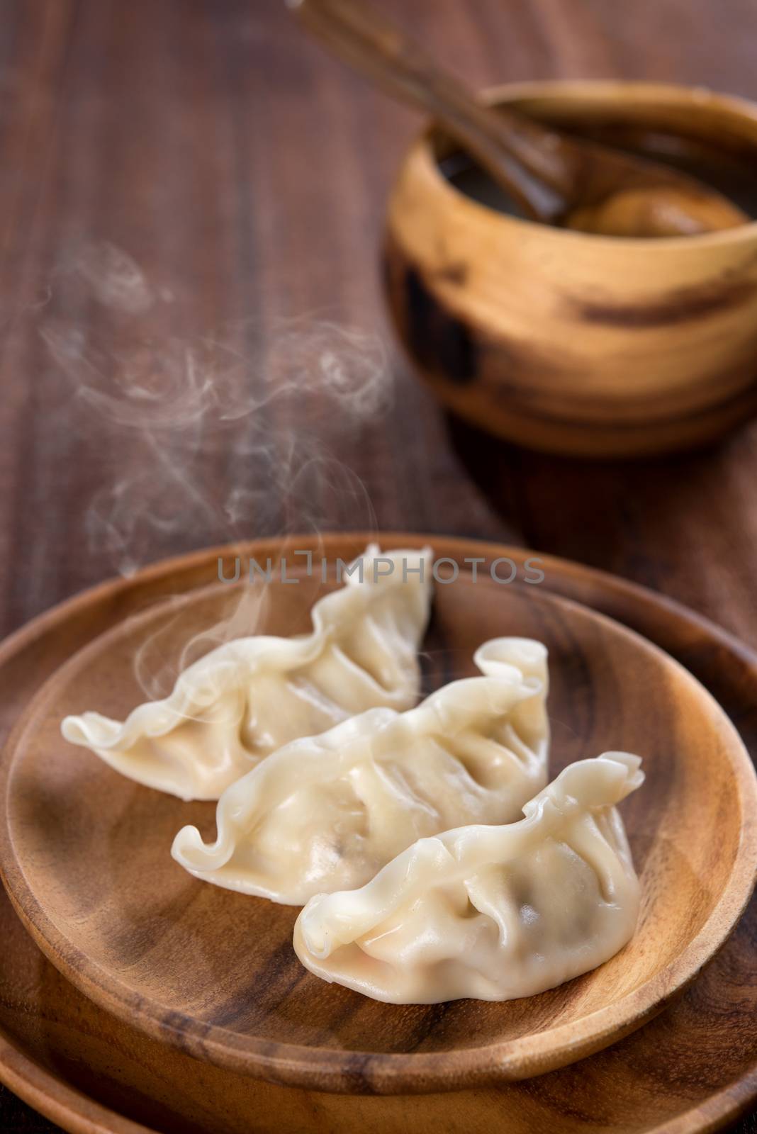 Fresh dumplings with hot steams on wood plate. Popular Chinese dish on rustic old vintage wooden background. 