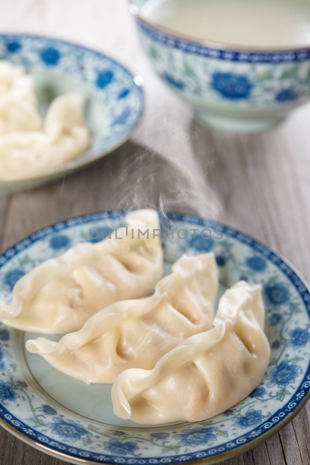Fresh dumpling on plate. Chinese cuisine on vintage wooden background. Fractal on the plate is generic print.
