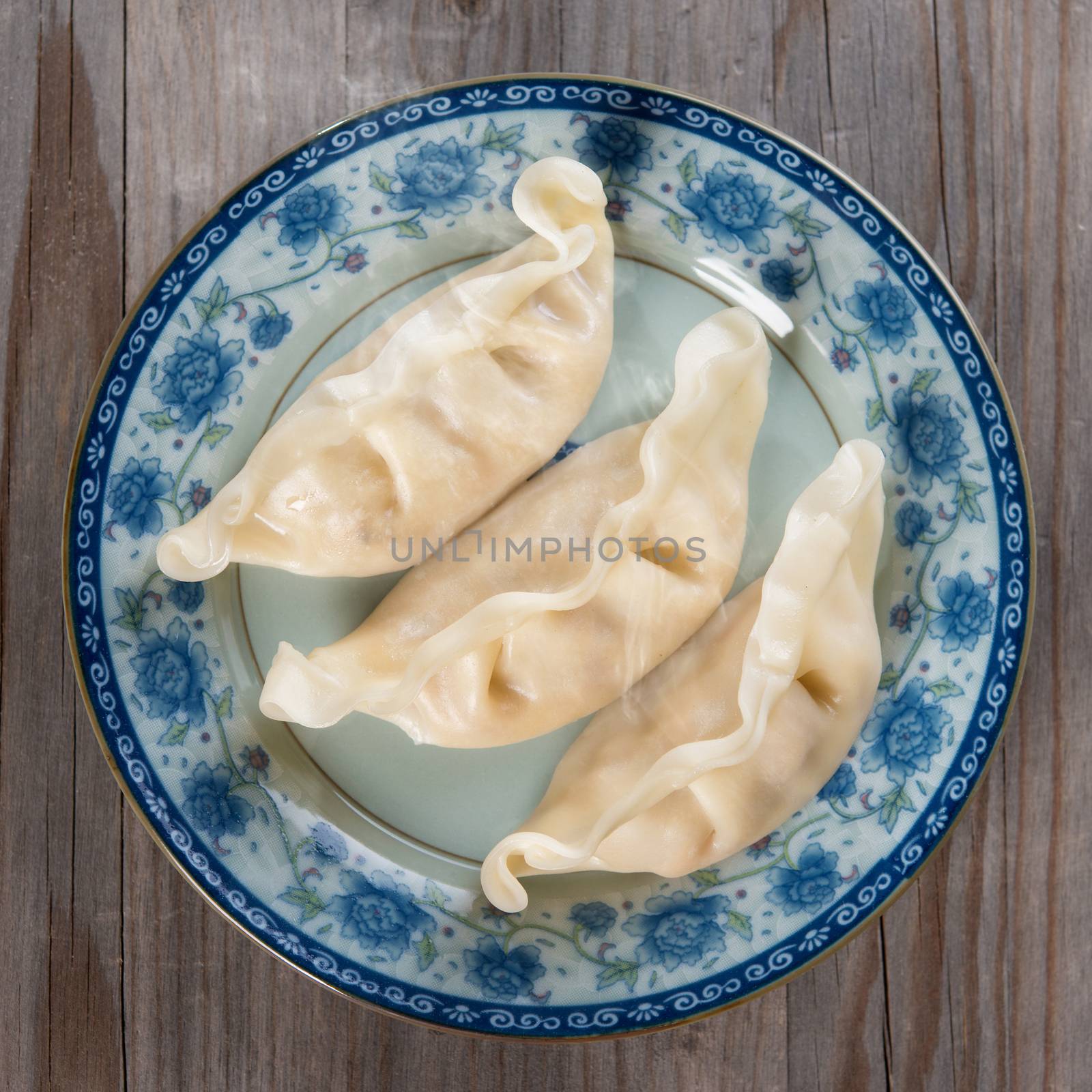 Top view fresh dumpling on plate. Chinese cuisine on vintage wooden background. Fractal on the plate is generic print.