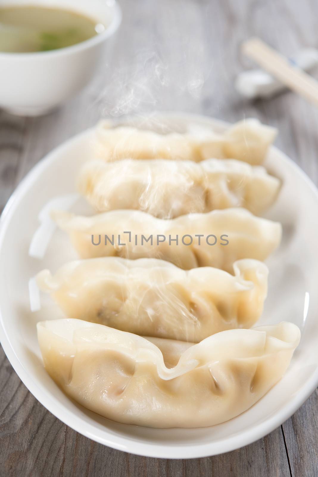 Close up fresh dumpling on plate with hot steams. Chinese food on old wooden background. 