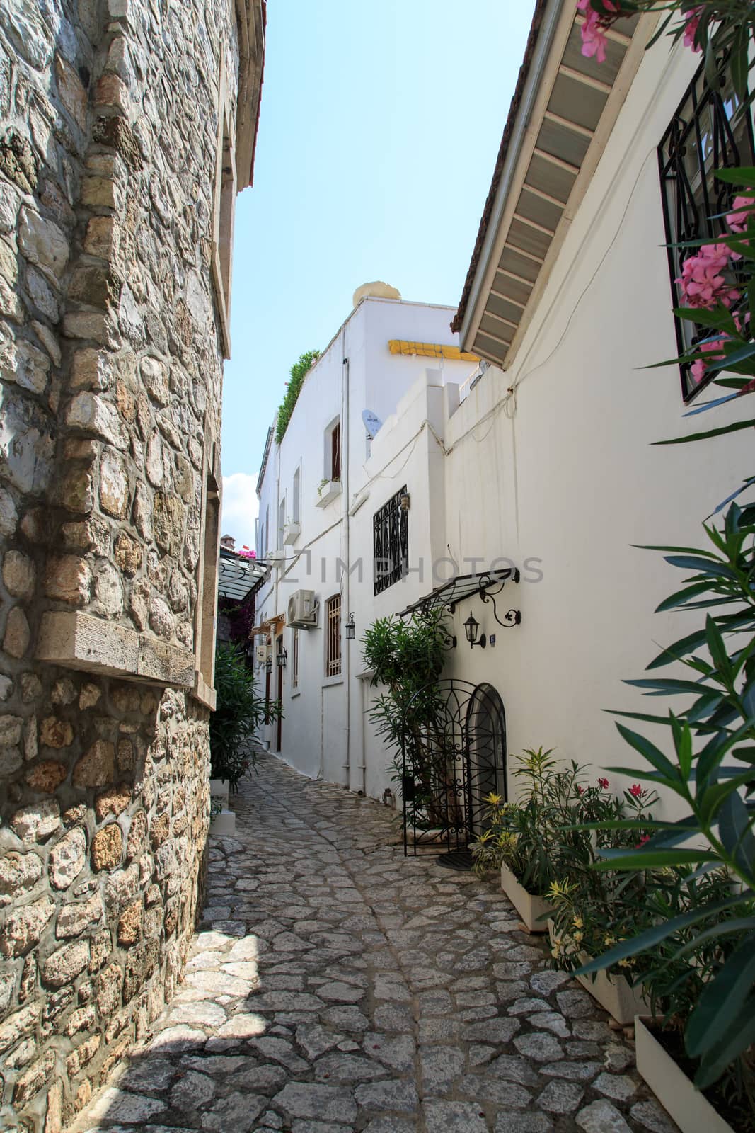 Historical stone houses and narrow street, under bright sunny sky.