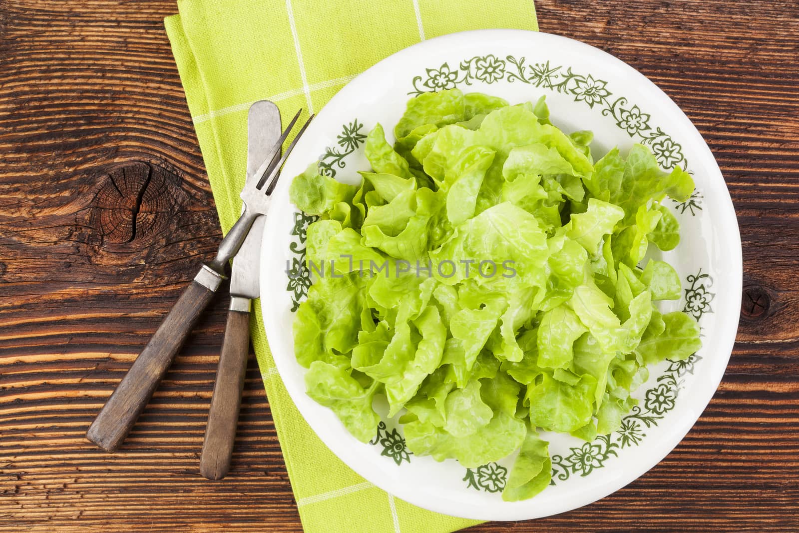 Fresh salad on plate on wooden background, top view. Healthy eating. 