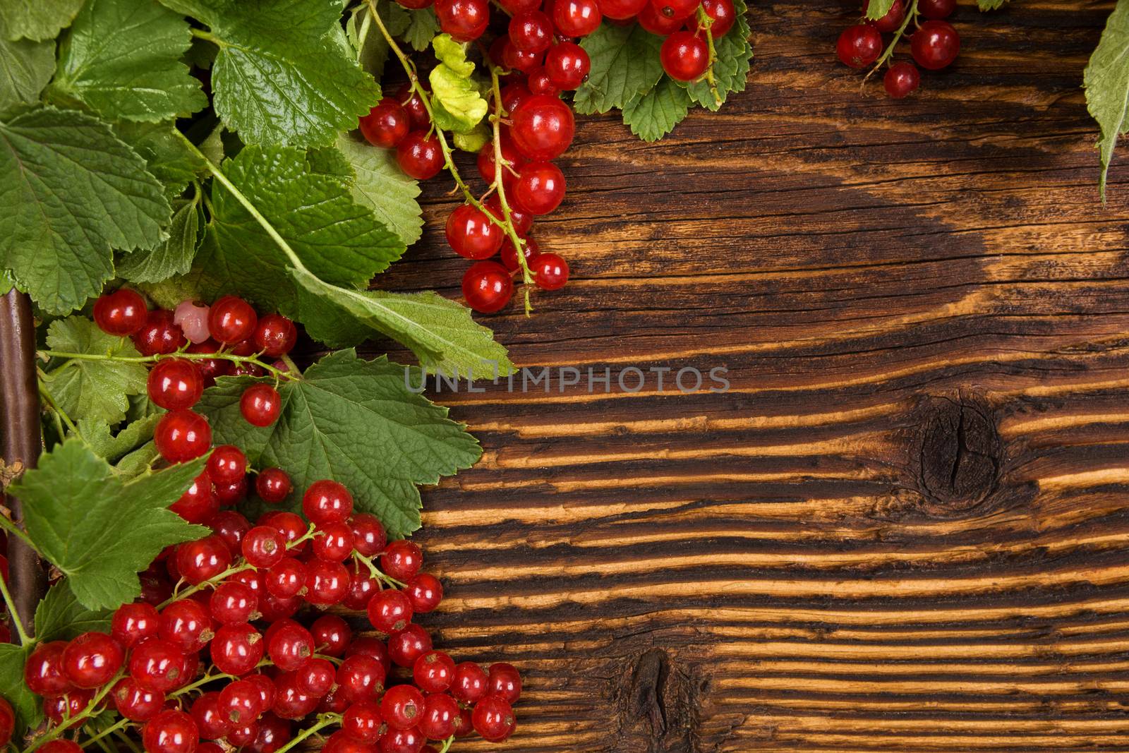 Red currant on wooden background. Healthy summer fruit eating.