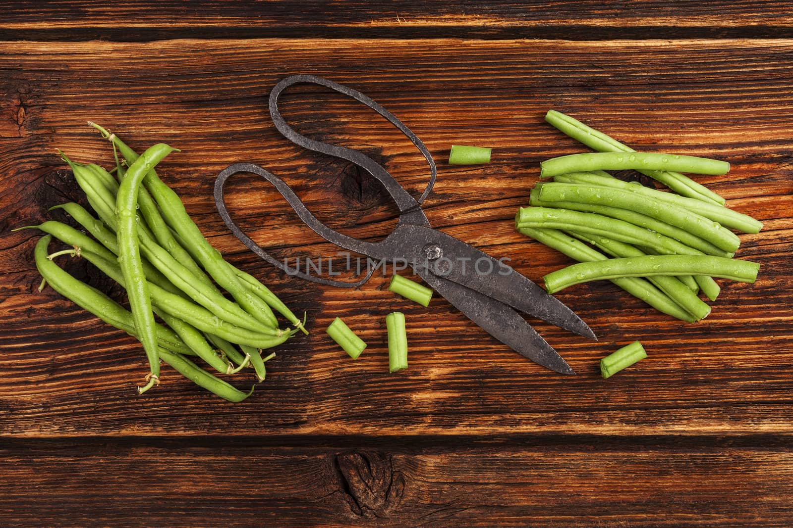 Fresh green beans with water drops on brown wooden textured table. Fresh vegetable eating. 