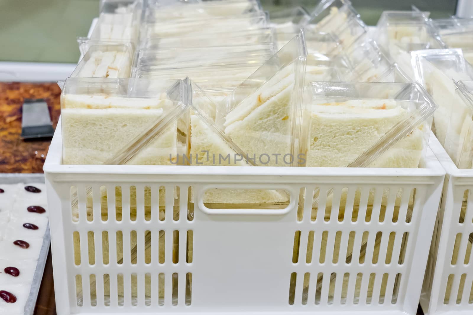 Cut platter of sandwich triangles in plastic box ready for sell