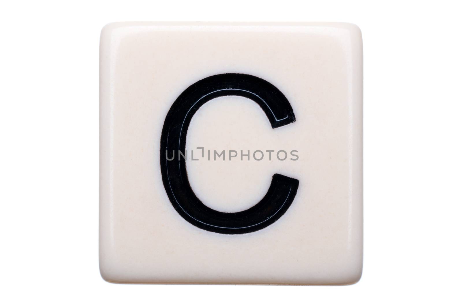 A macro shot of a game tile with the letter C on it on a white background.
