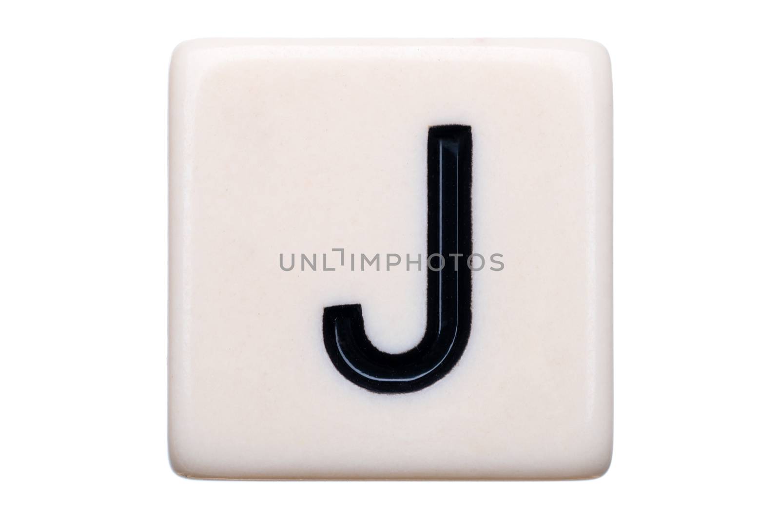 A macro shot of a game tile with the letter J on it on a white background.