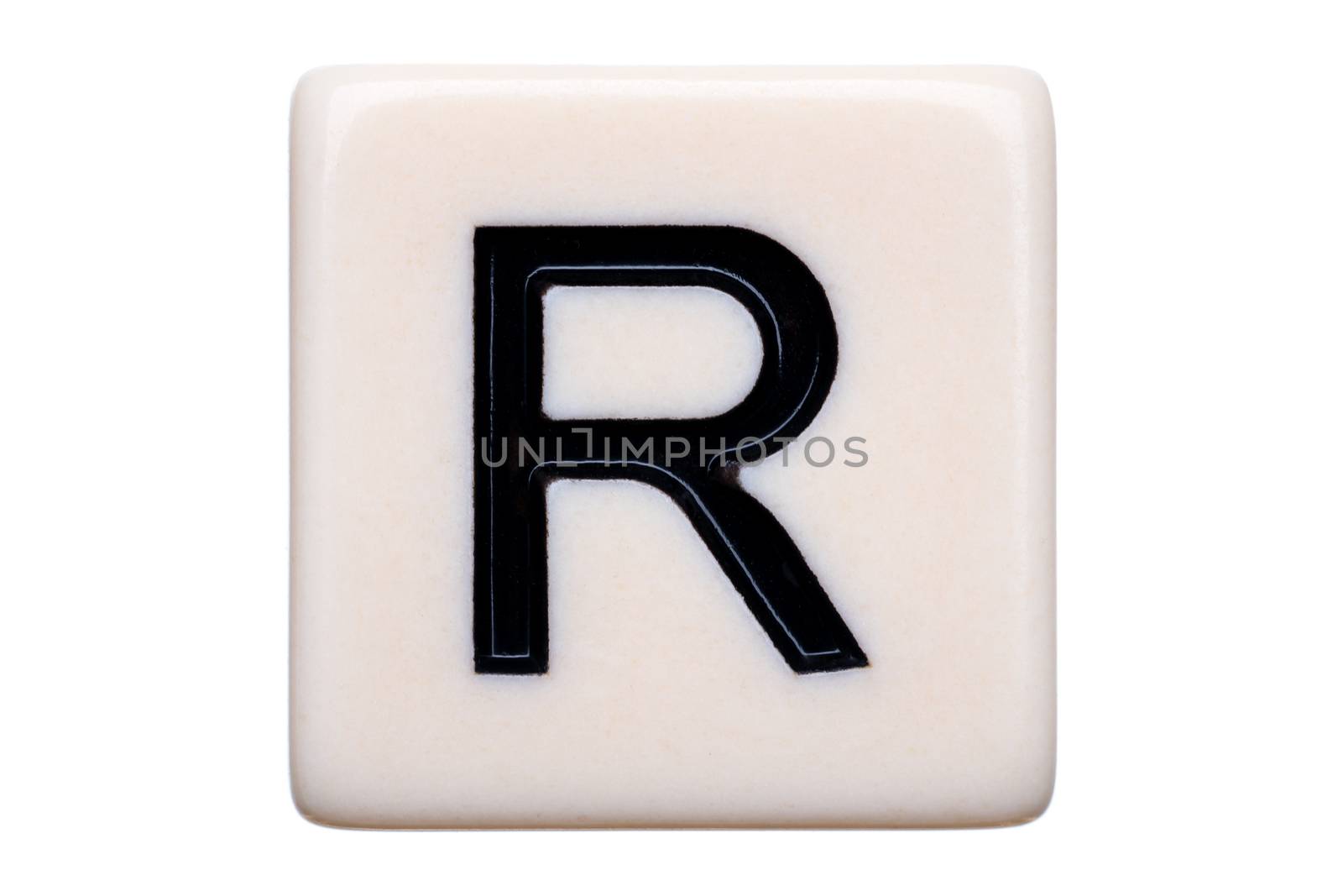 A macro shot of a game tile with the letter R on it on a white background.