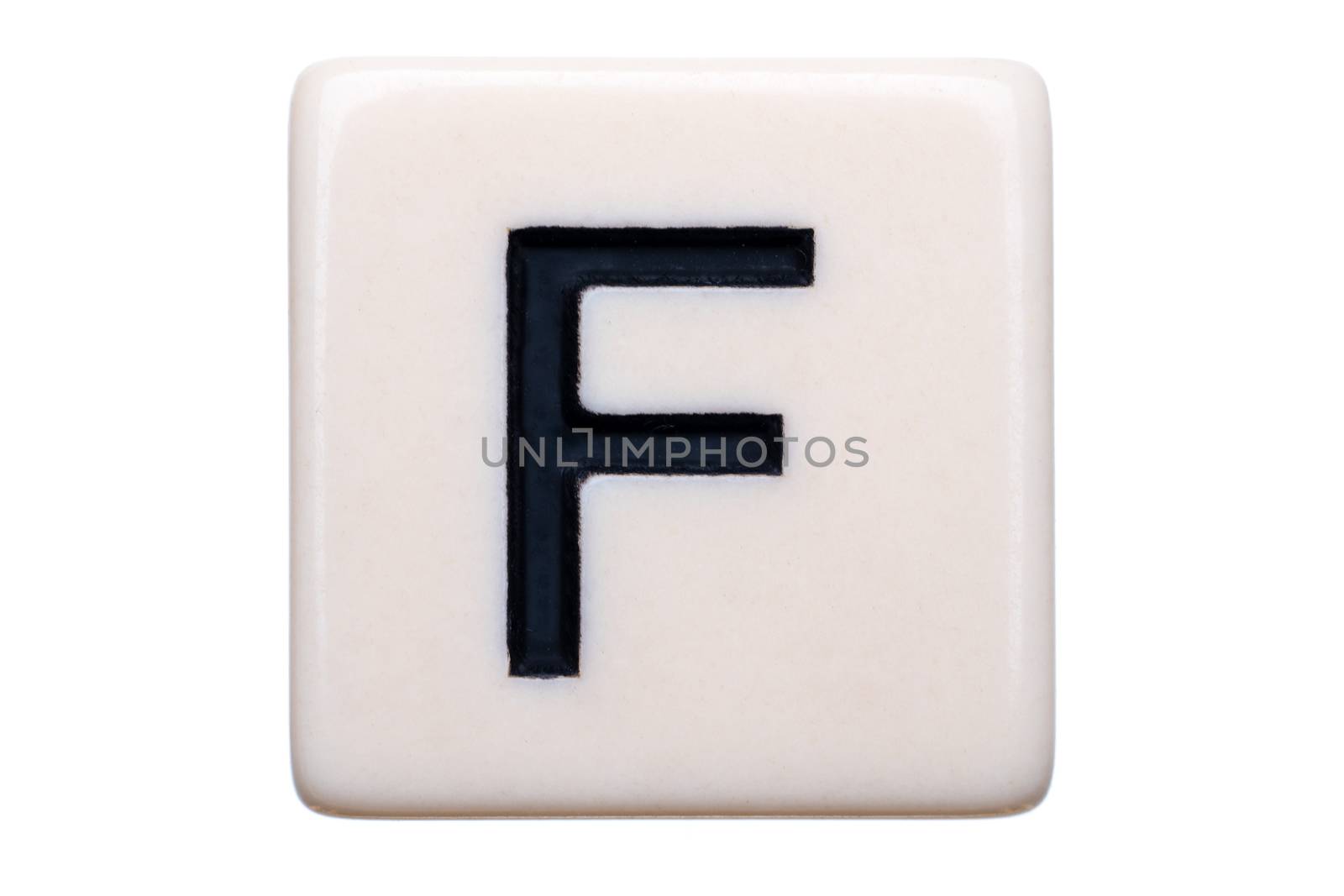 A macro shot of a game tile with the letter F on it on a white background.