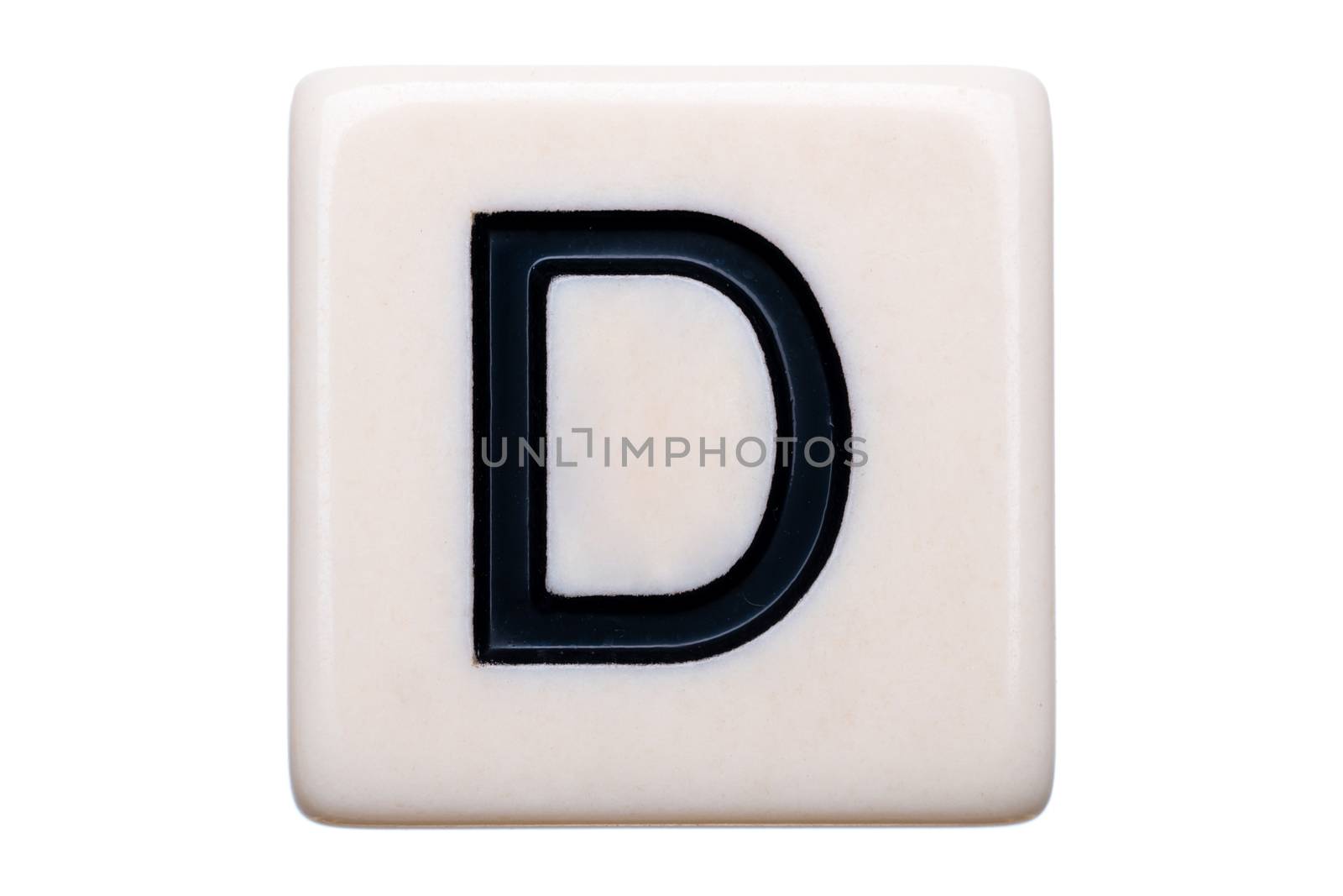 A macro shot of a game tile with the letter D on it on a white background.