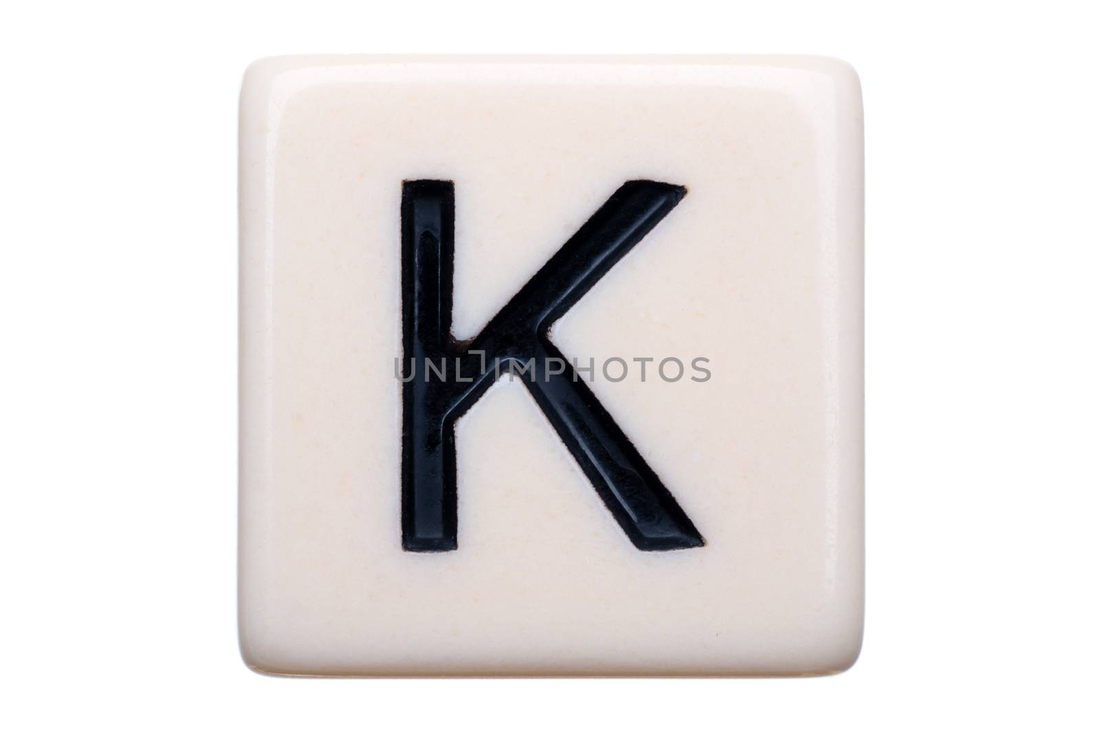 A macro shot of a game tile with the letter K on it on a white background.