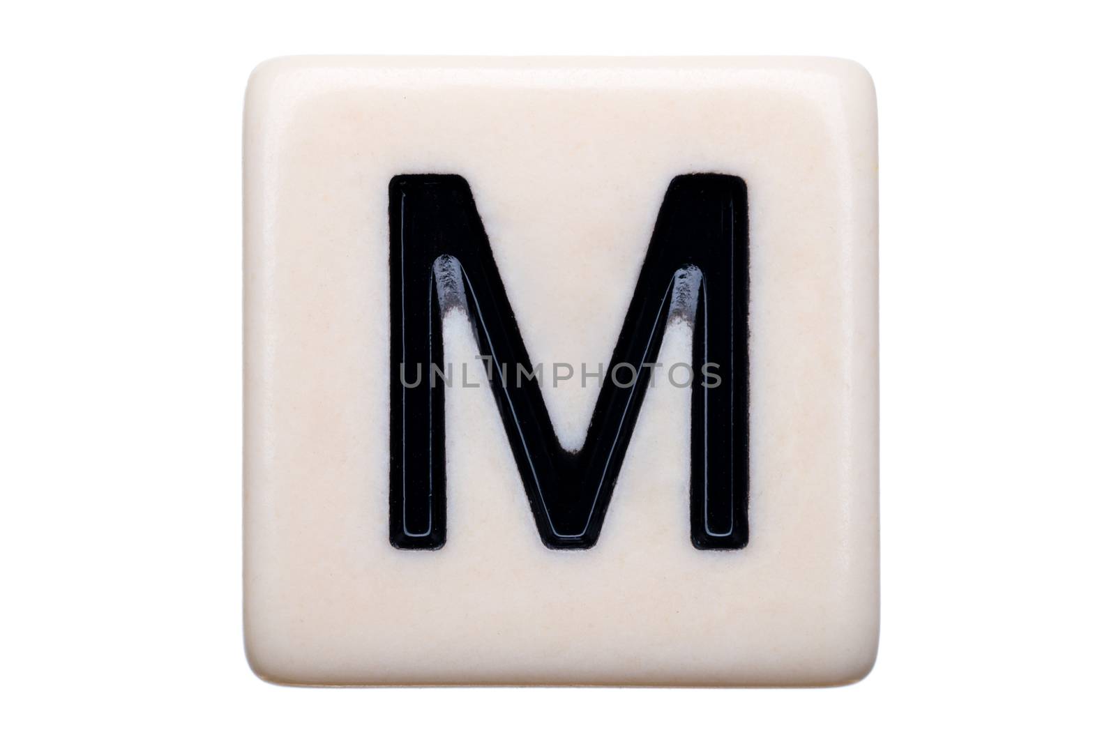 A macro shot of a game tile with the letter M on it on a white background.
