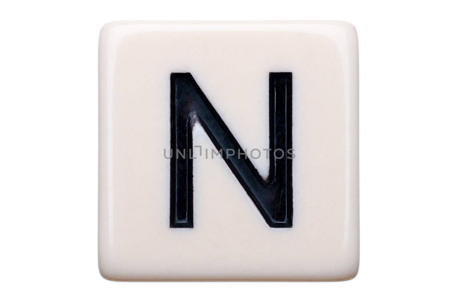 A macro shot of a game tile with the letter N on it on a white background.