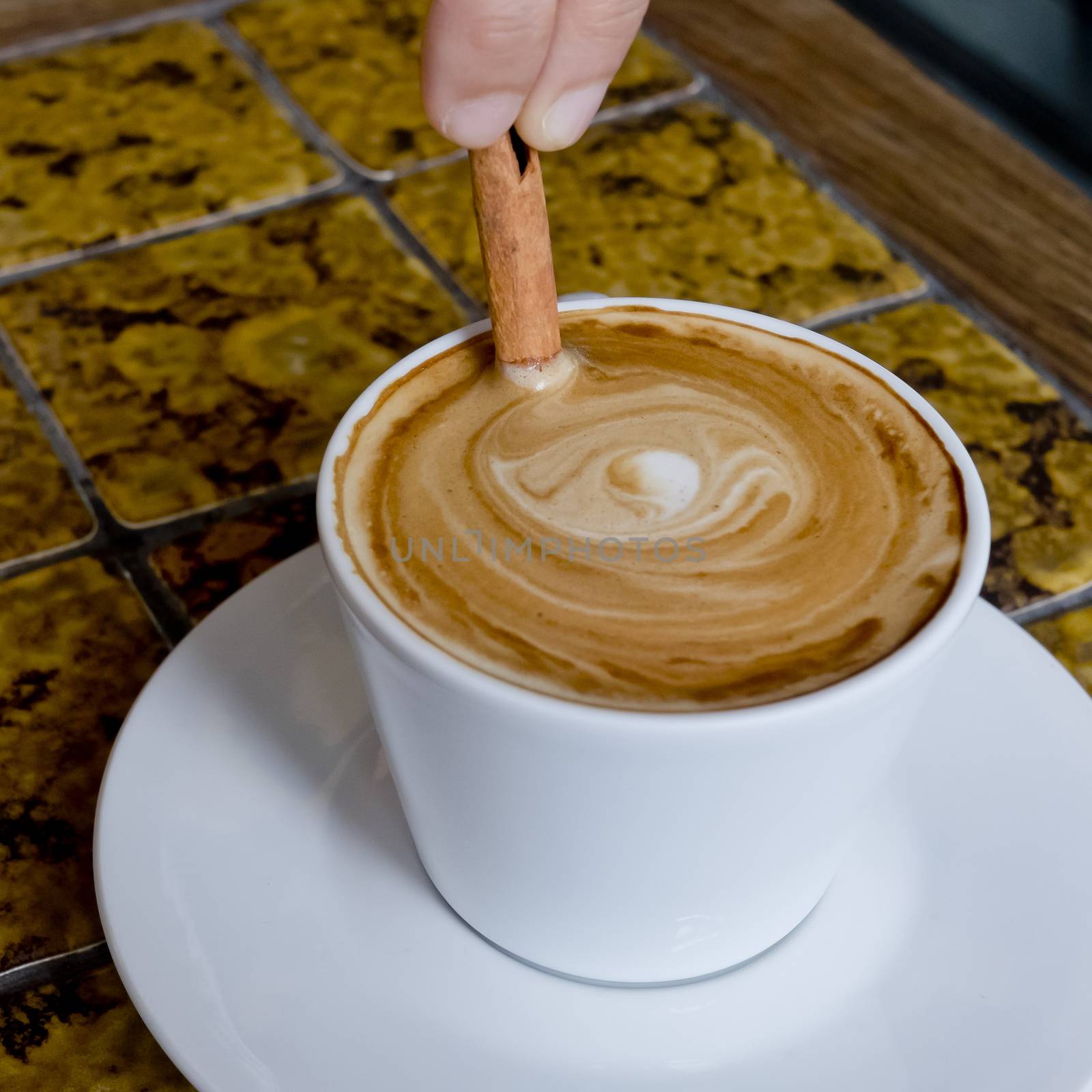 A coffee cup Latte being stirred by Cinnamon sticks. by art9858