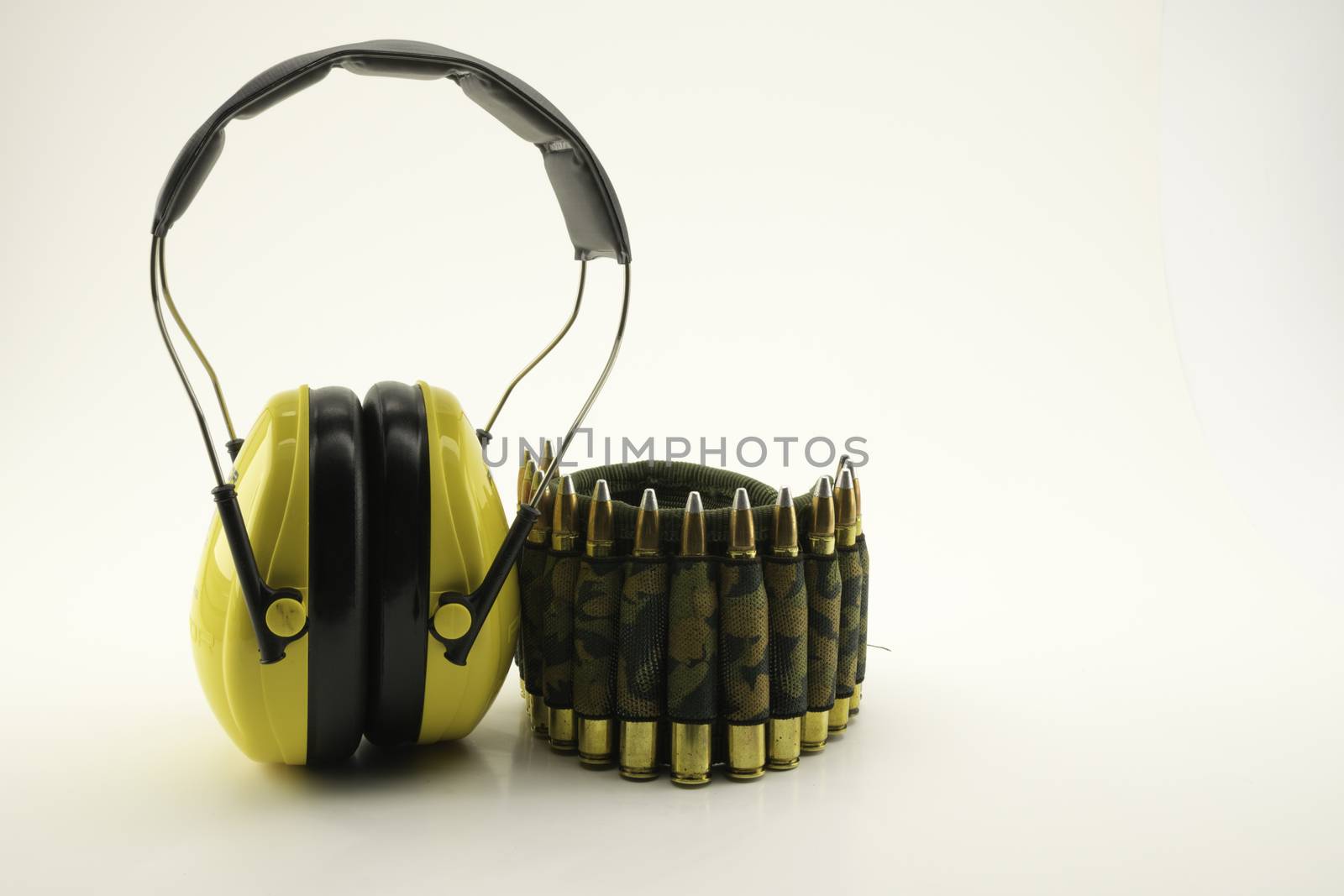 yellow ear protection and camouflage ammunition belt for rifle on white background