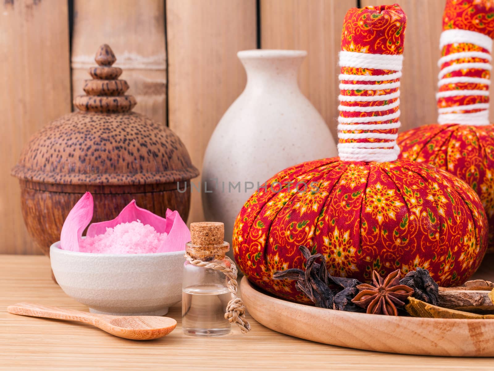 Natural Spa Ingredients herbal compress ball and essential Oil for alternative medicine and relaxation Thai Spa theme with bamboo background.