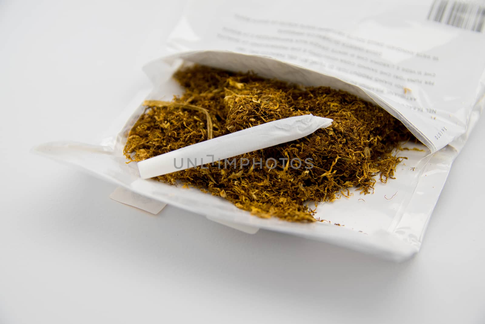 tobacco and hand made cigarette on white background