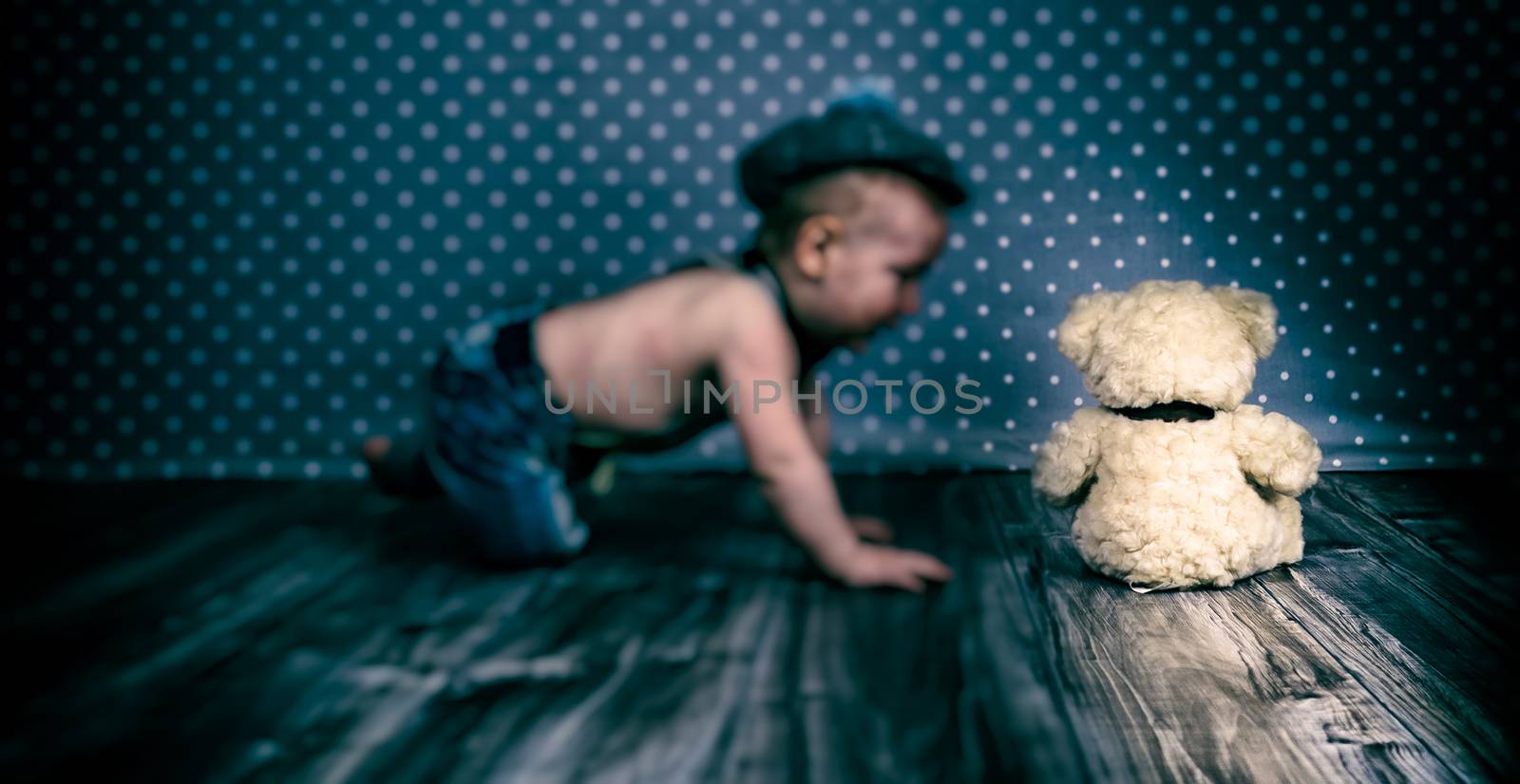 child with vintage hat and suspenders playing with teddy bear