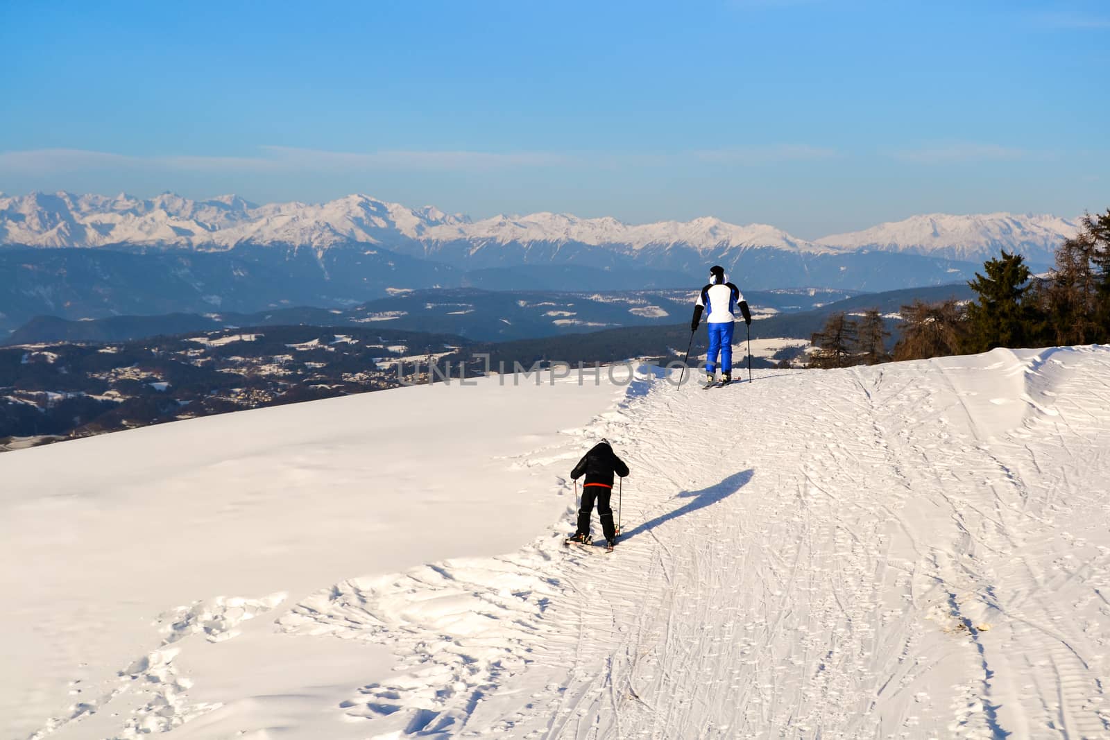 ORTISEI, ITALY - CIRCA DECEMBER 2012: Father and son skiing on the snowy slopes of the Alps.