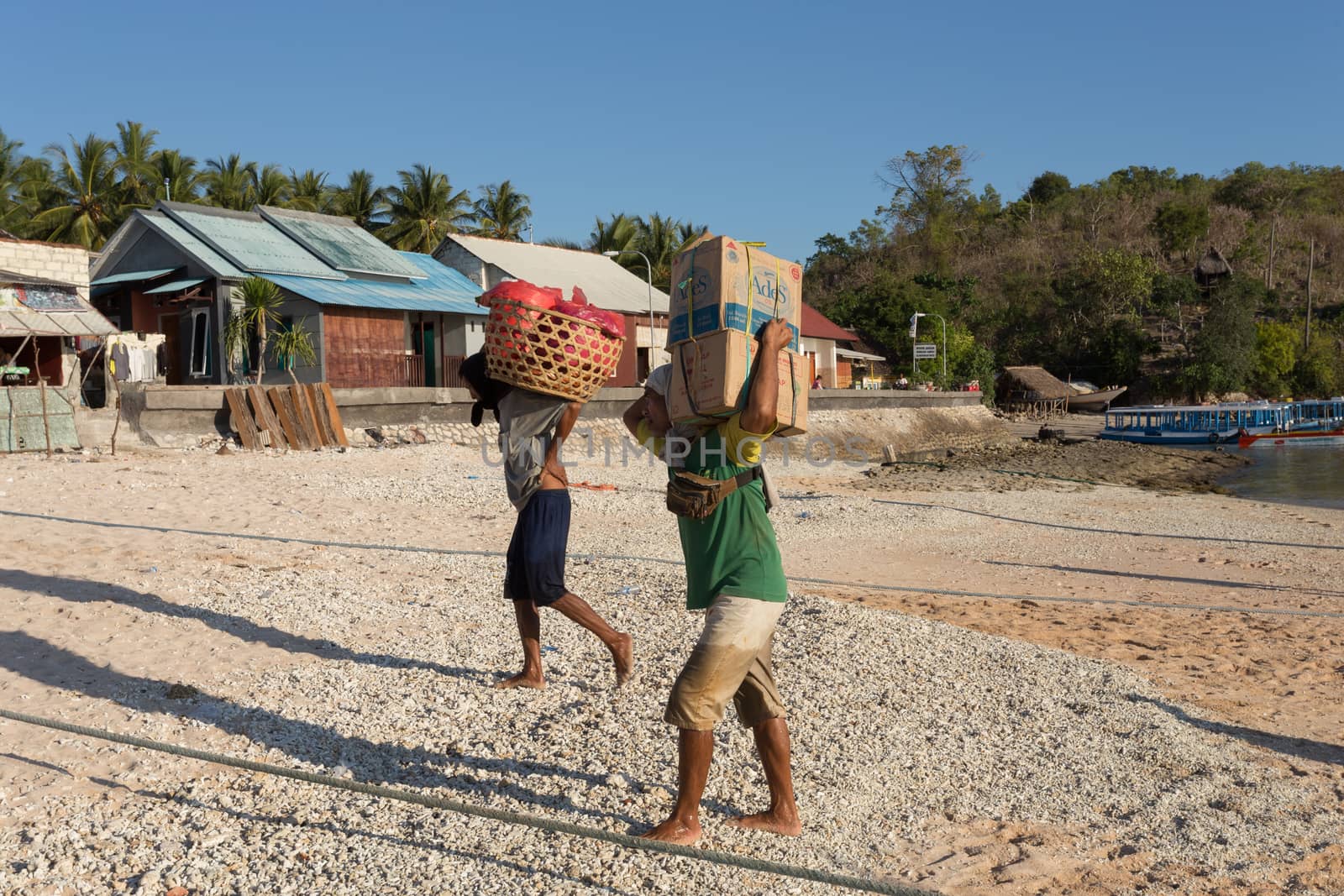 BALI, NUSA PENIDA ISLAND, INDONESIA - JULY 27.2015: Men transports cargo from ship in the hands. There is no other possibility to transport. Nusa Penida July 27. 2015 Indonesia