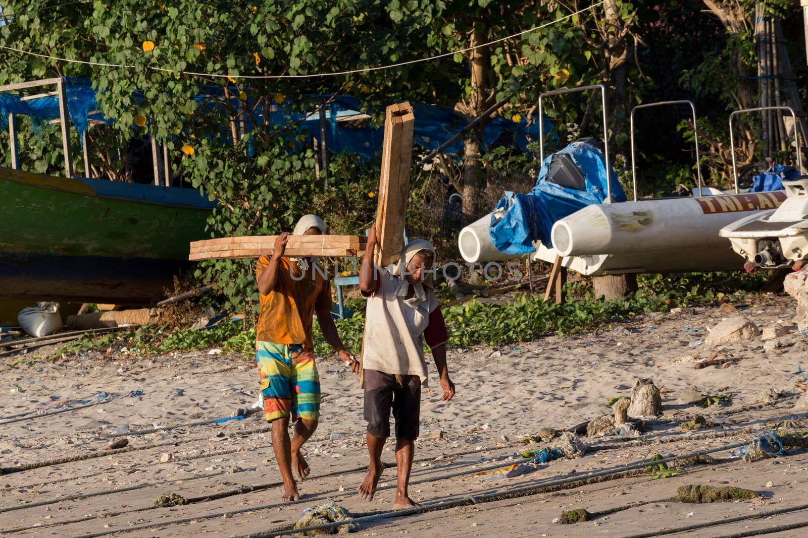 BALI, NUSA PENIDA ISLAND, INDONESIA - JULY 27.2015: Men transports cargo from ship to the shipyard in the hands. There is no other possibility to transport. Nusa Penida July 27. 2015 Indonesia