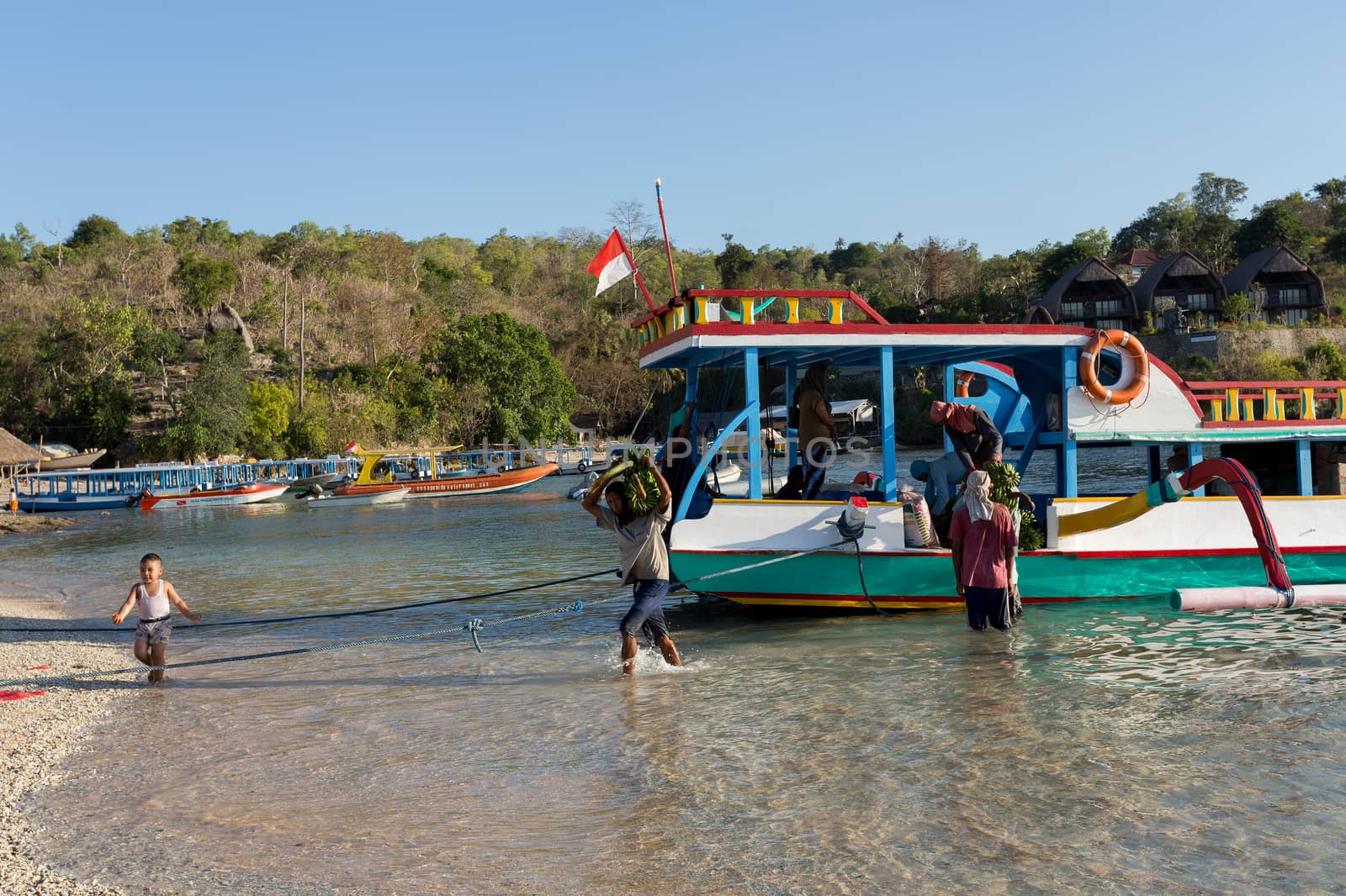BALI, NUSA PENIDA ISLAND, INDONESIA - JULY 27.2015: Men transports cargo from ship in the hands. There is no other possibility to transport. Nusa Penida July 27. 2015 Indonesia