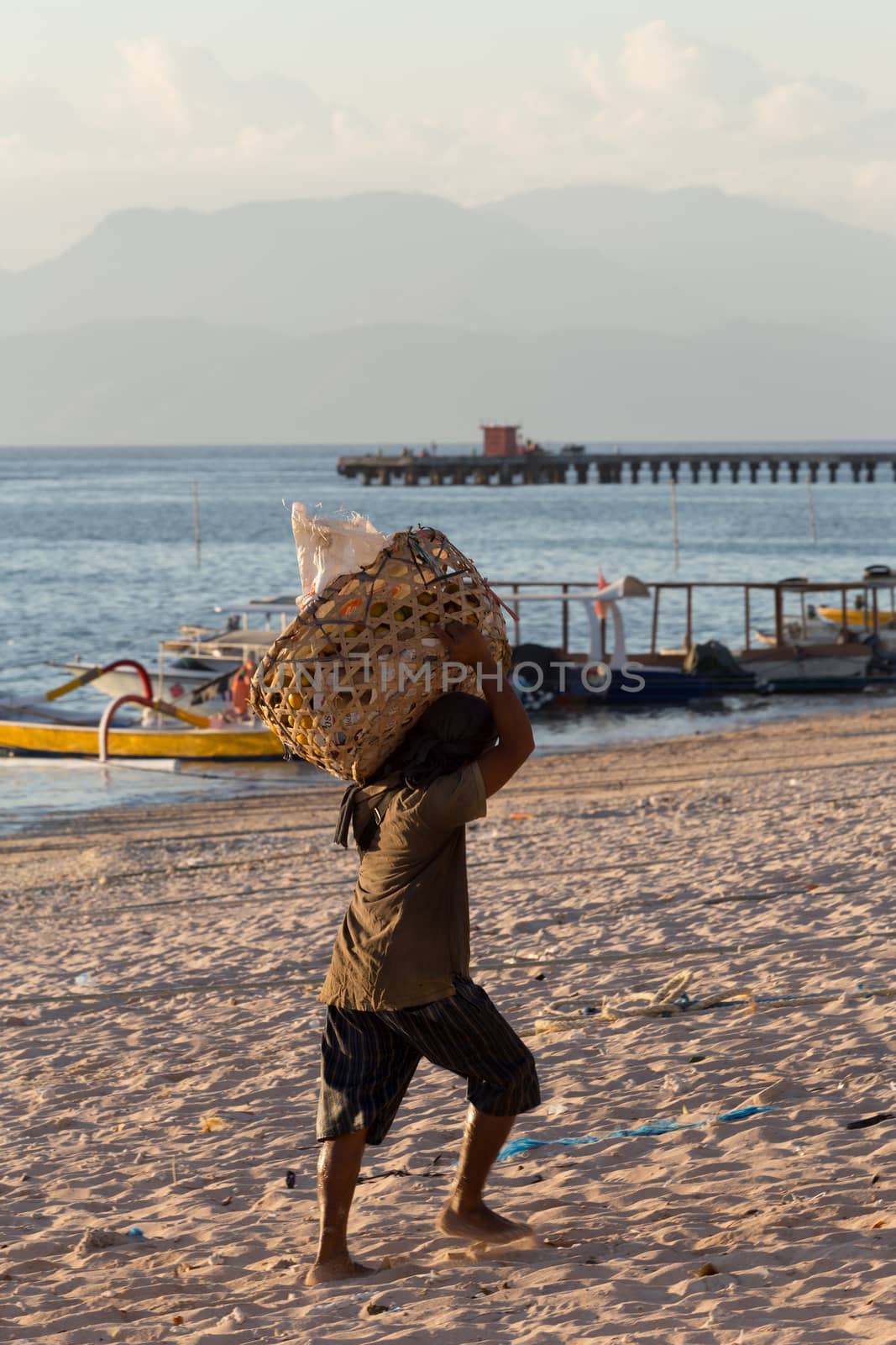 BALI, NUSA PENIDA ISLAND, INDONESIA - JULY 27.2015: Men transports cargo from ship in the hands. There is no other possibility to transport. Nusa Penida July 27. 2015 Indonesia