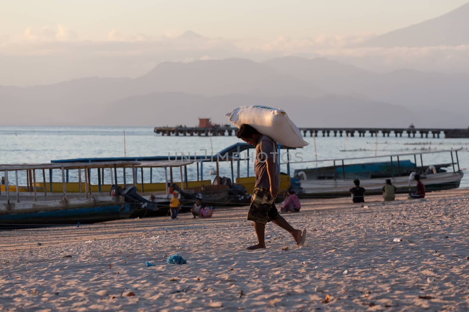 BALI, NUSA PENIDA ISLAND, INDONESIA - JULY 27.2015: Men transports cargo from ship in the hands. There is no other possibility to transport. Nusa Penida July 27. 2015 Indonesia