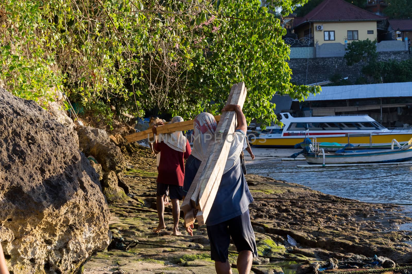 BALI, NUSA PENIDA ISLAND, INDONESIA - JULY 27.2015: Men transports cargo from ship to the shipyard in the hands. There is no other possibility to transport. Nusa Penida July 27. 2015 Indonesia
