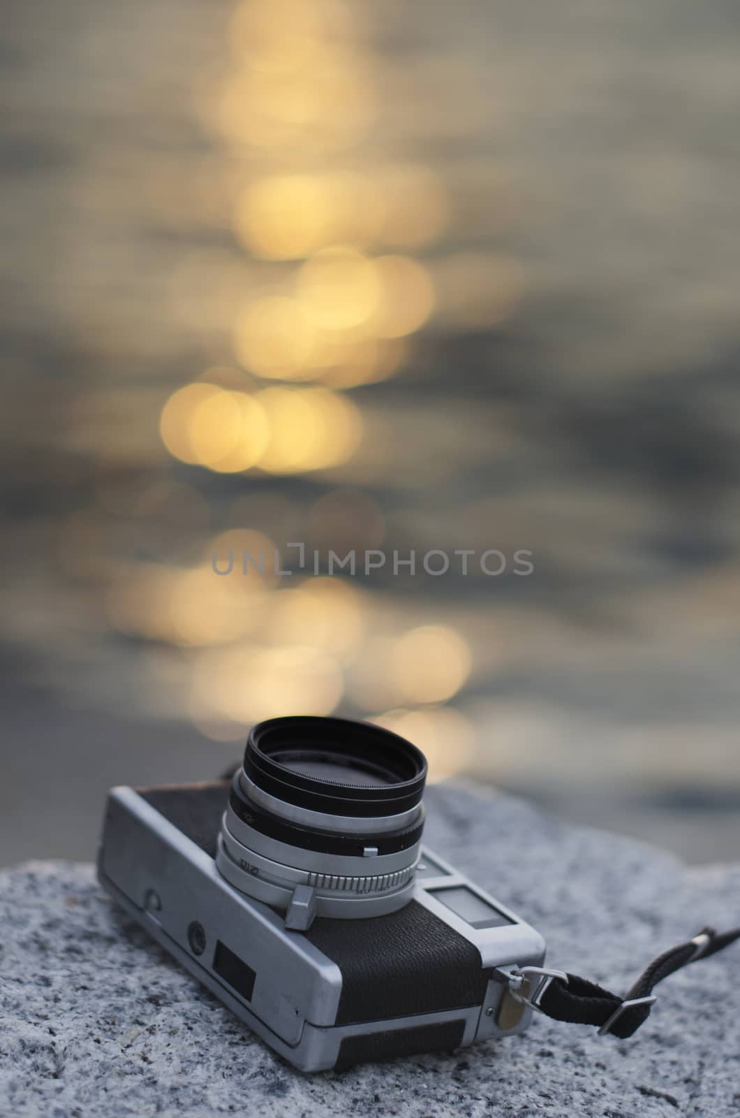 Relax with vintage camera beside sea with sunset reflected bokeh by pixbox77