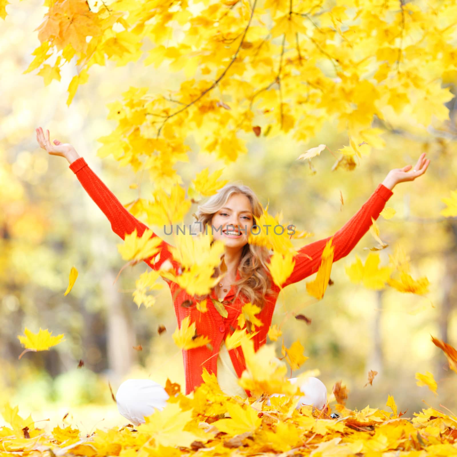 Happy woman throwing autumn leaves in the park