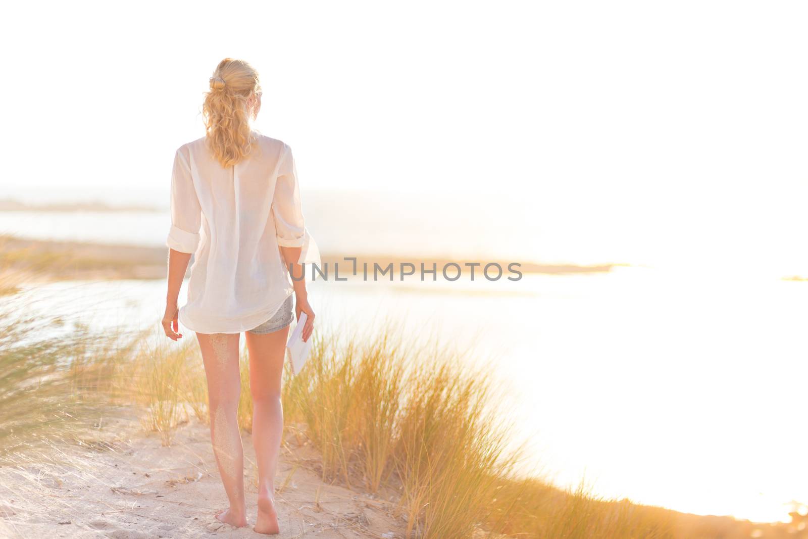 Relaxed woman enjoying freedom and life an a beautiful sandy beach.  Young lady feeling free, relaxed and happy. Concept of happiness, enjoyment and well being.  Enjoying Sun on Vacations. Copyspace.