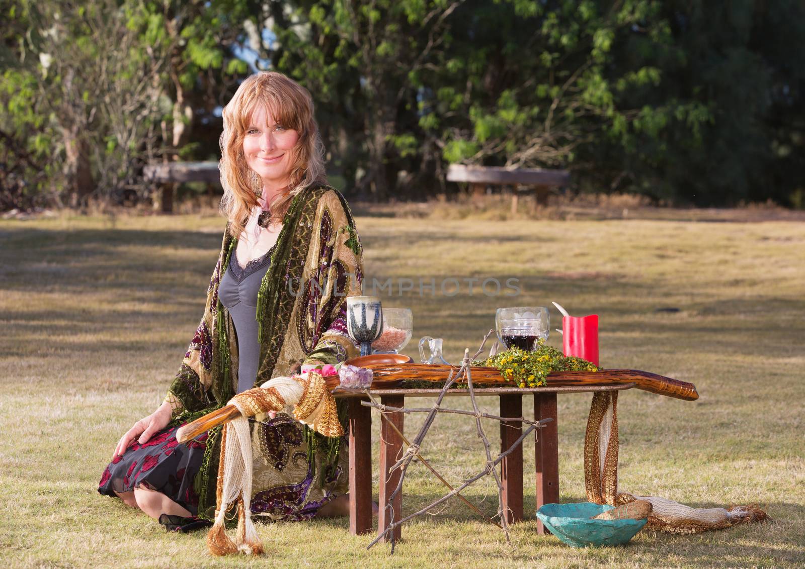 Beautiful female witch sitting on ground with altar