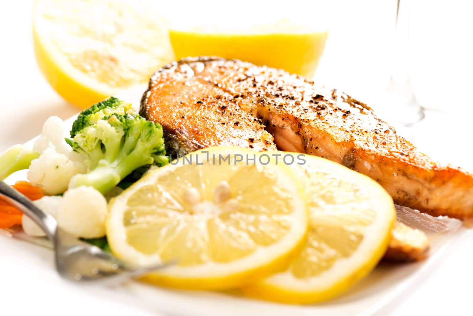 Grilled salmon and vegetables on white plate selective focus by Nanisimova