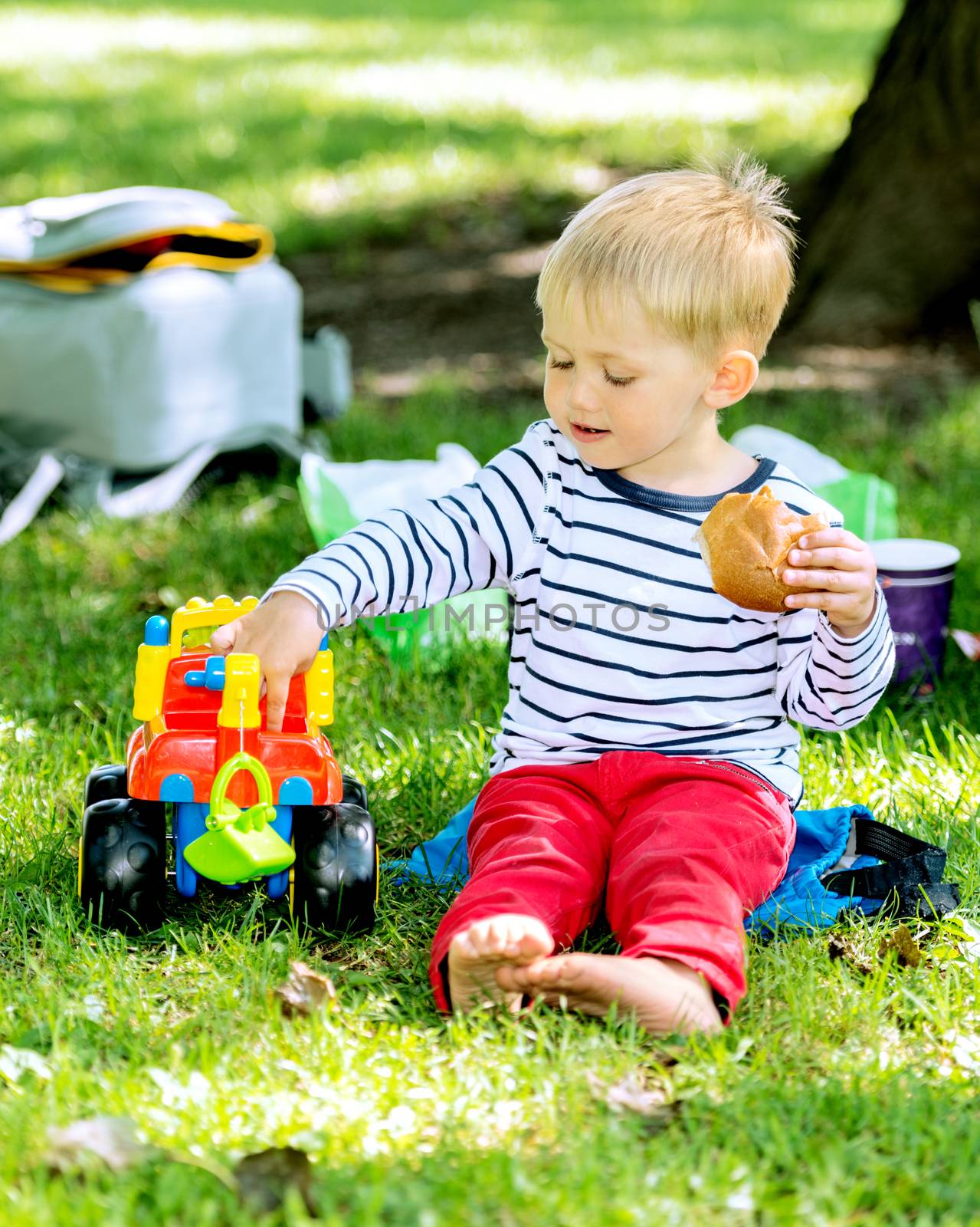 Little preschool boy playing with big toy car and having fun, outdoors.