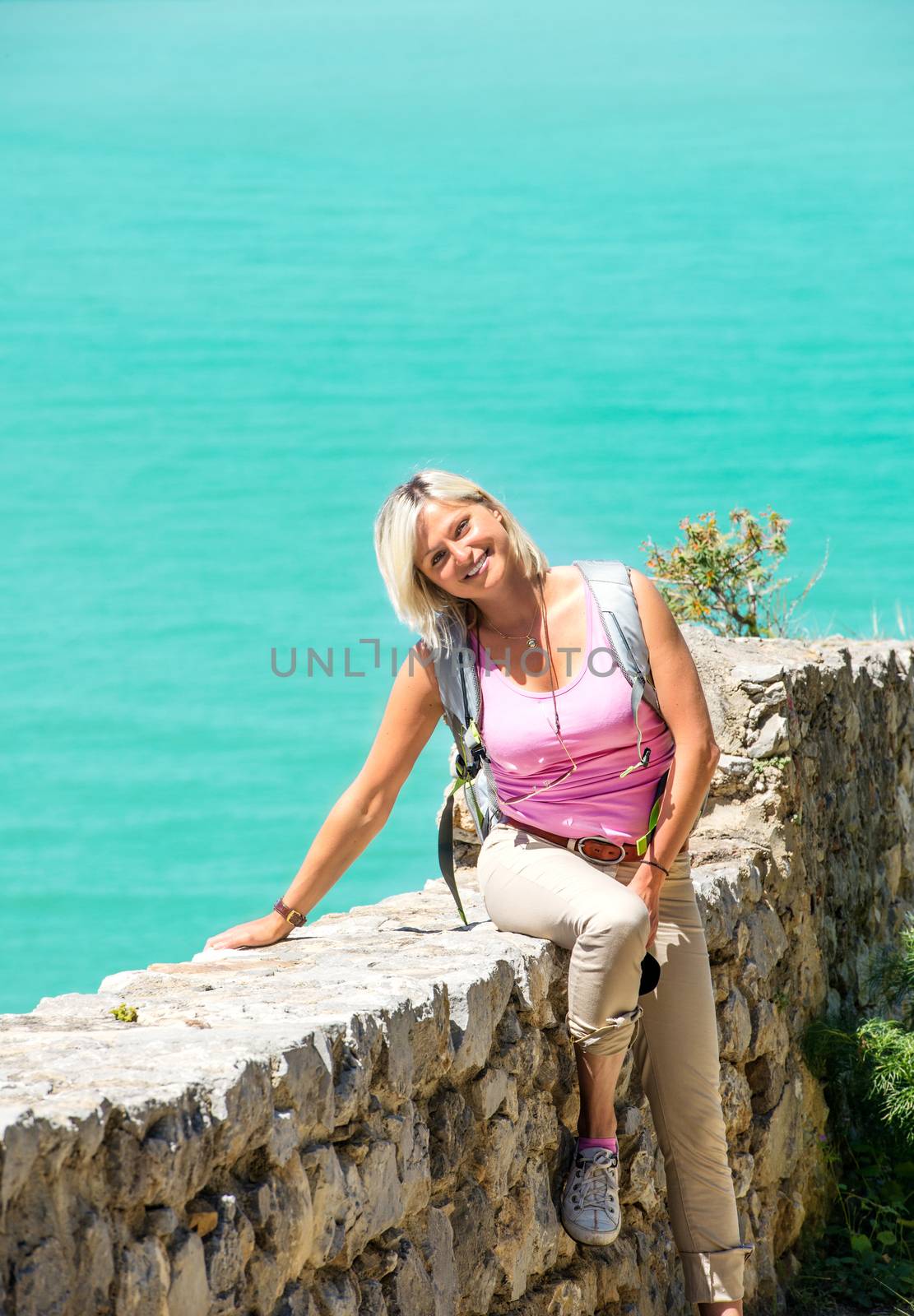 Young smiling woman sitting on stone wall