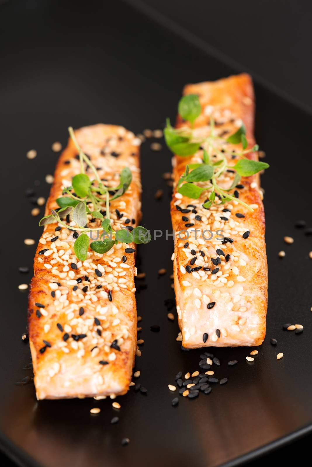 Grilled salmon on black plate vertical by Nanisimova