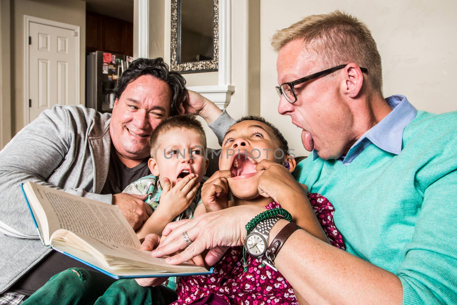 Homosexual parents reading and making faces with son and daughter