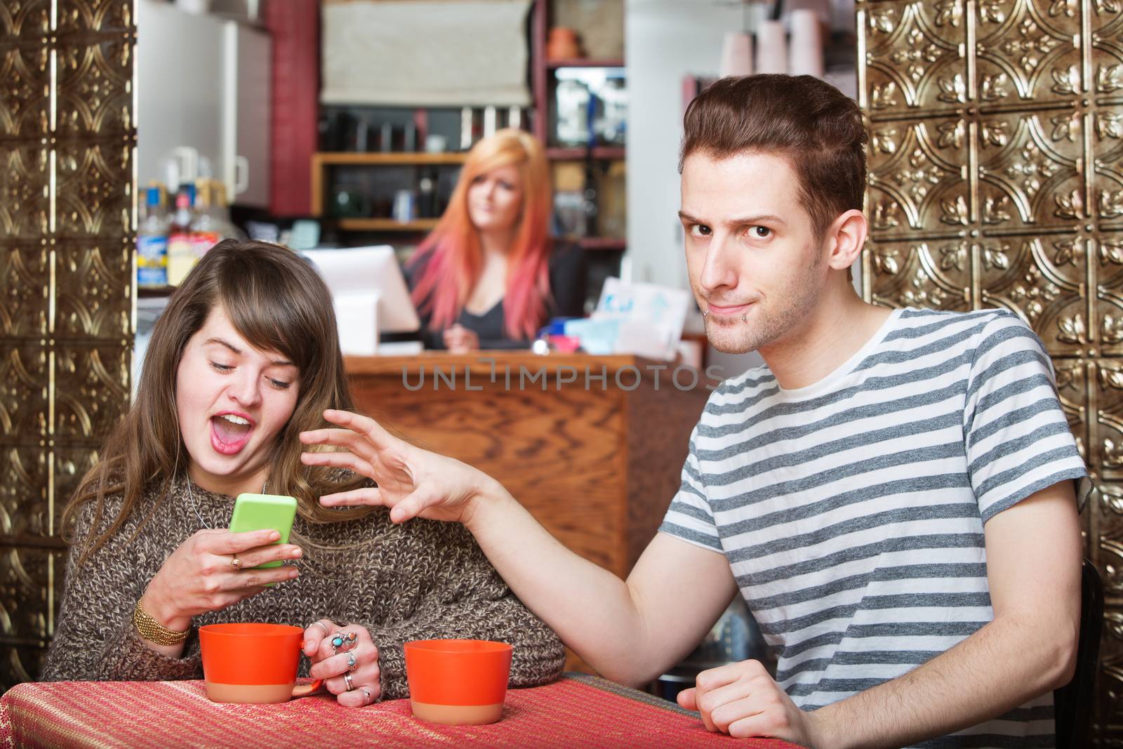 Annoyed man in cafe snatching phone from woman