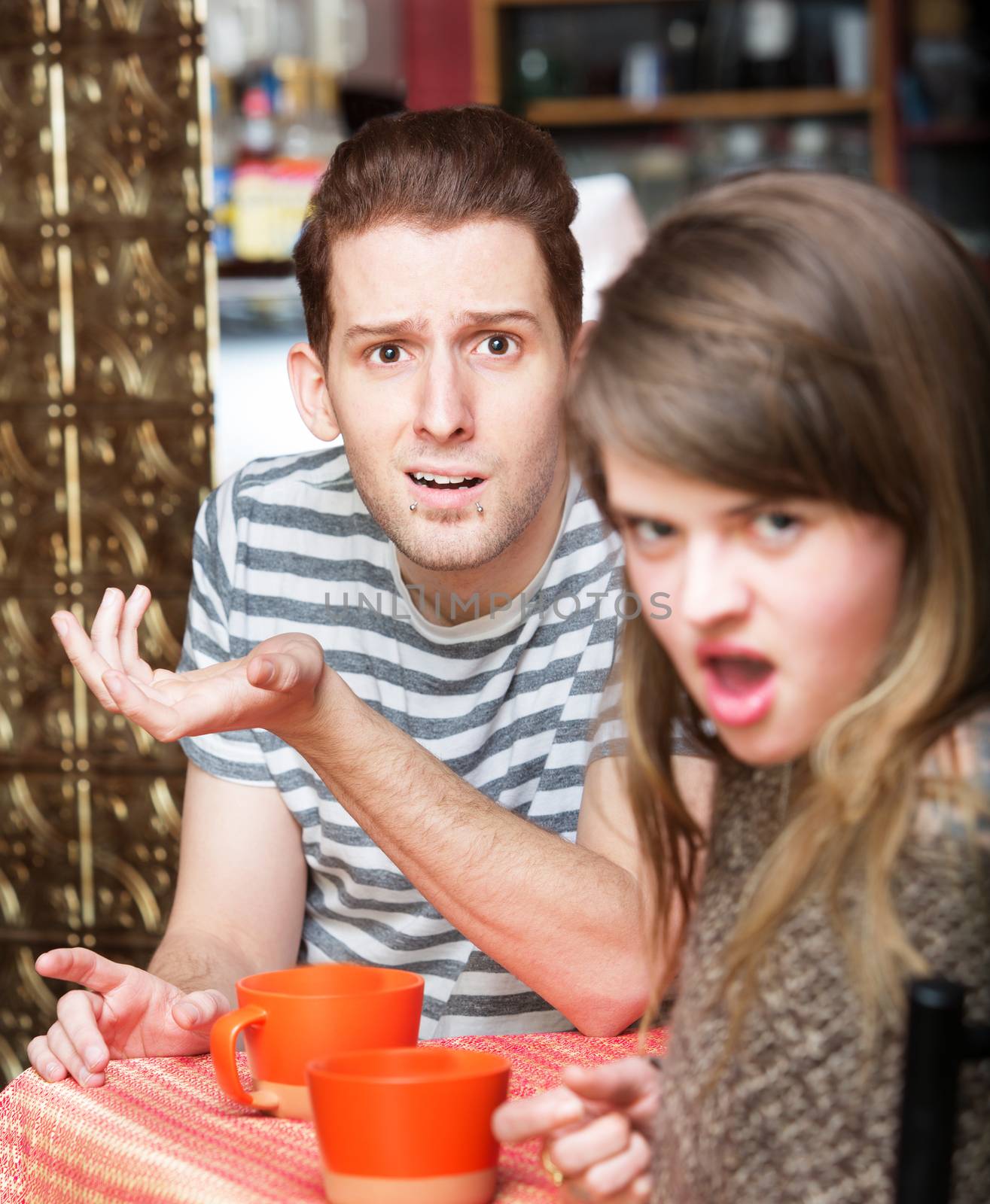 Disgusted young woman with frustrated man at cafe
