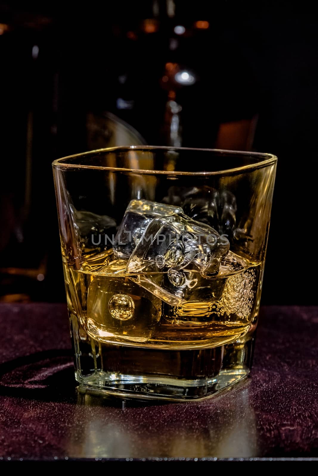 glass of whiskey on wood table with bottles in background, warm atmosphere, time of relax with whisky with space for text
