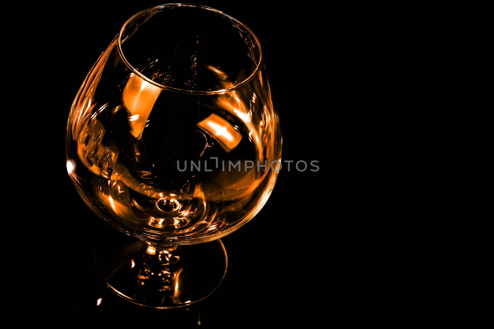 empty snifter of brandy in elegant typical cognac glass on black background with space for text