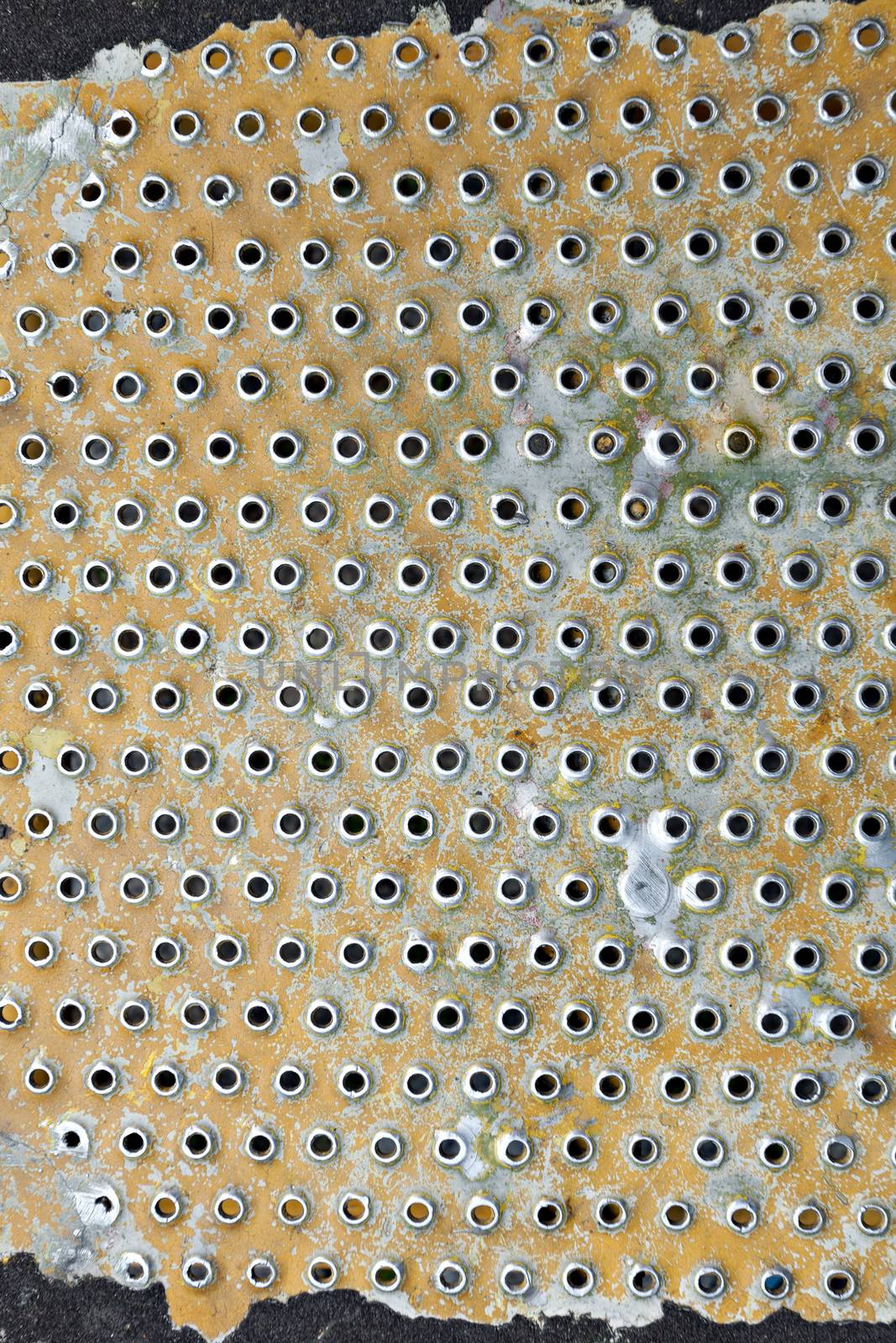 Old worn steel grate material close up painted yellow and worn.